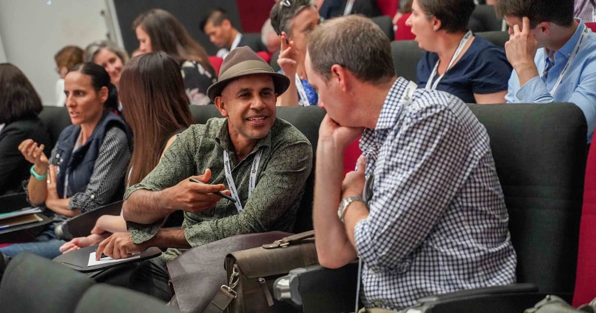Two men sitting next to each other at Change Conference, having a discussion.
